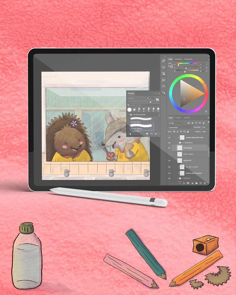 Una tableta apoyada sobre una tela rosa muestra una ilustración en proceso: dos personajes animales en una escena de interior, con la paleta de capas y la rueda de color abiertas, y un lápiz óptico al lado.